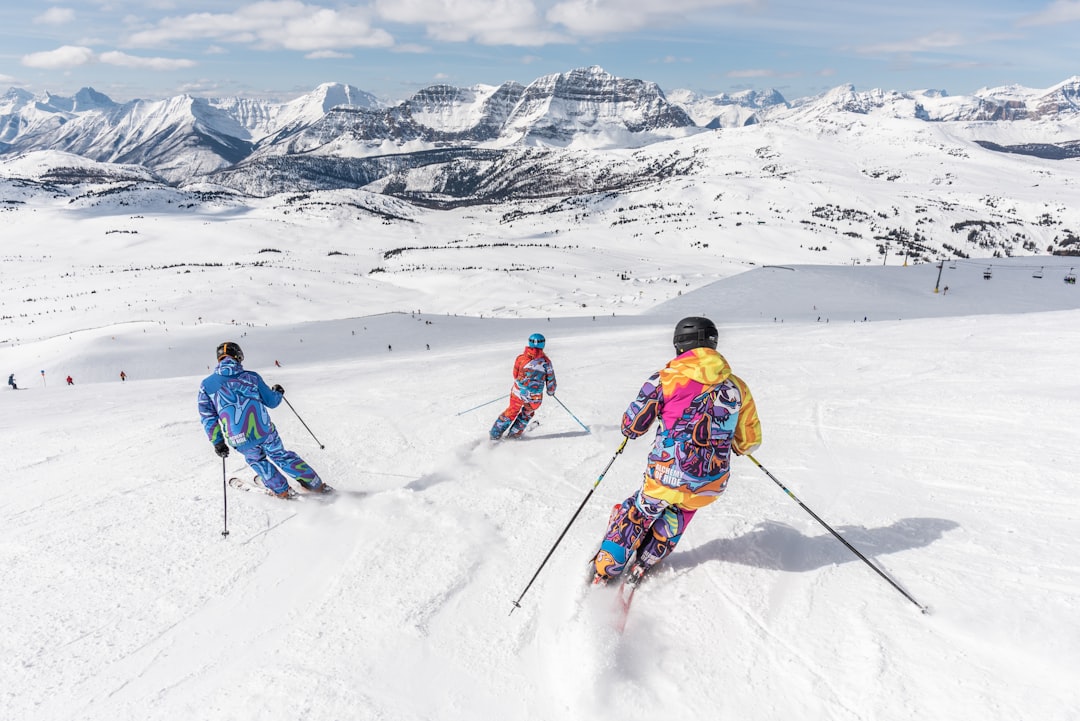 2-person-in-yellow-jacket-and-blue-helmet-riding-ski-blades-on-snow-covered-mountain-during-uobe-wj-suk