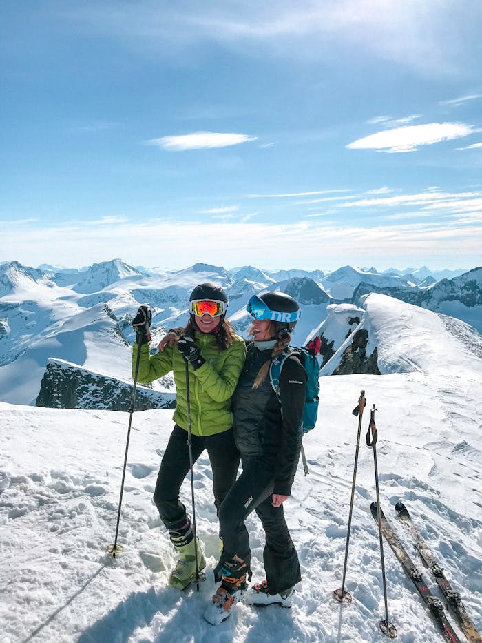 two-women-skiing-on-snow-2197924 Two skiers enjoy a sunny winter day on a snowy mountain peak with stunning panoramic views.